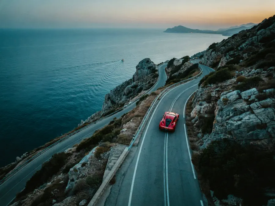 Superdeportivo rojo en una carretera de montaña junto al mar